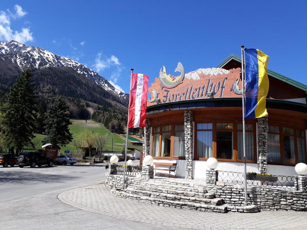施内贝格山麓普赫贝格Hotel-Restaurant Forellenhof的一座有旗帜的建筑,前面有山