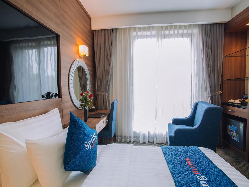 河内Spring Hotel Hanoi的酒店客房,配有一张床和一张蓝色椅子