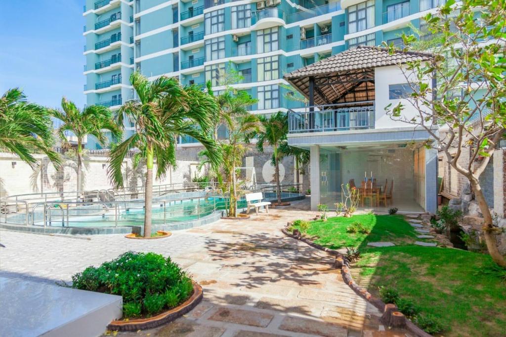 头顿Rio TD5 homestay的一座大型公寓楼,设有游泳池和棕榈树