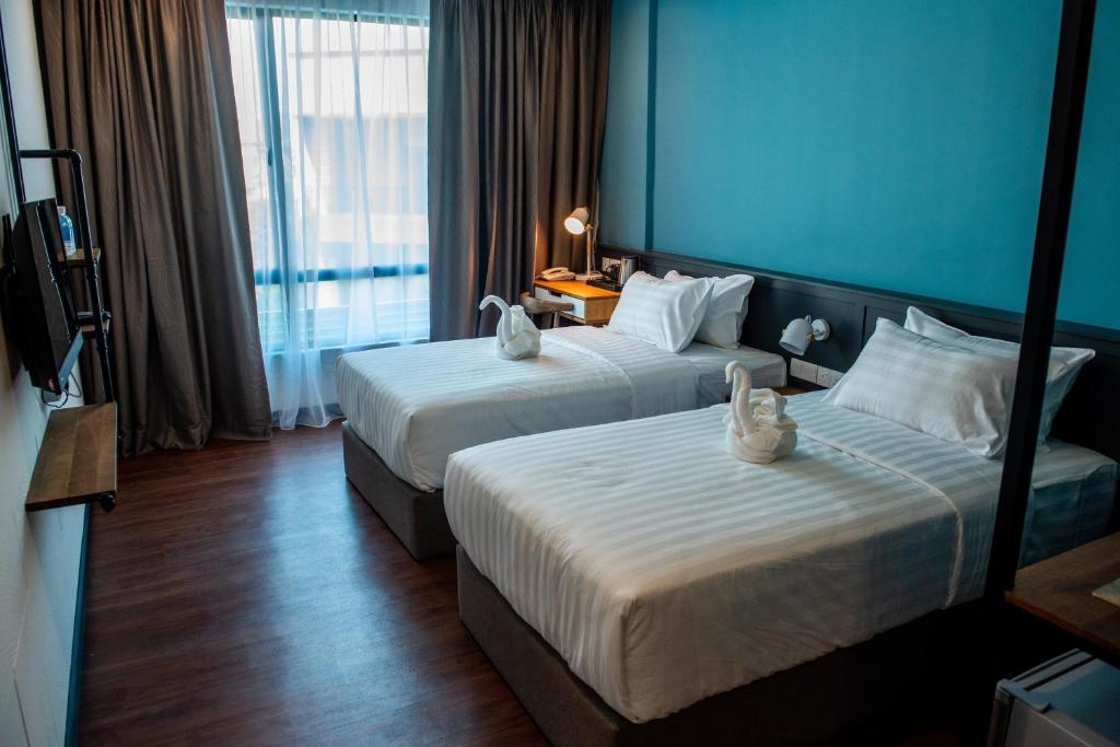 巴力文打O&G Hotel Parit Buntar的两张位于酒店客房的床,拥有蓝色的墙壁