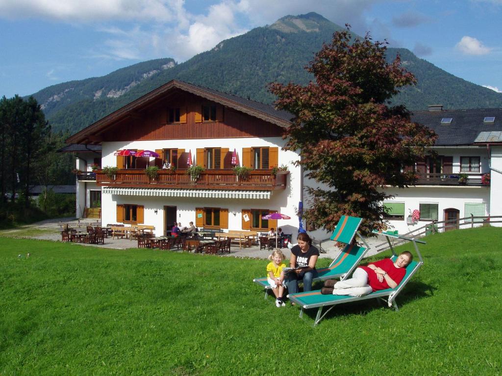 施特罗布尔Hotel Garni Pension zur Wacht的一群人坐在房子前面的草坪椅上