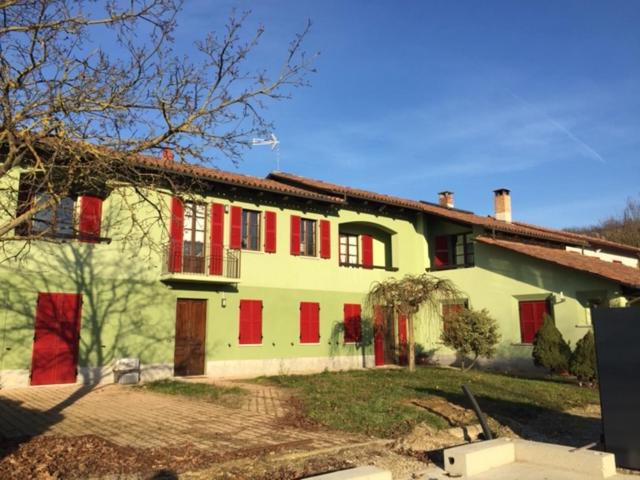 科斯蒂廖莱达斯蒂La Cascina dei Banditi的红色的黄色房子,红色的百叶窗