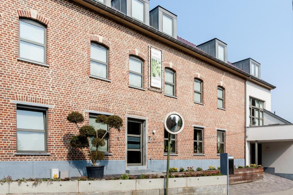 Onze-Lieve-Vrouw-Lombeek盖斯特恩豪弗特尔罗米贝克酒店的前面有植物的红砖建筑