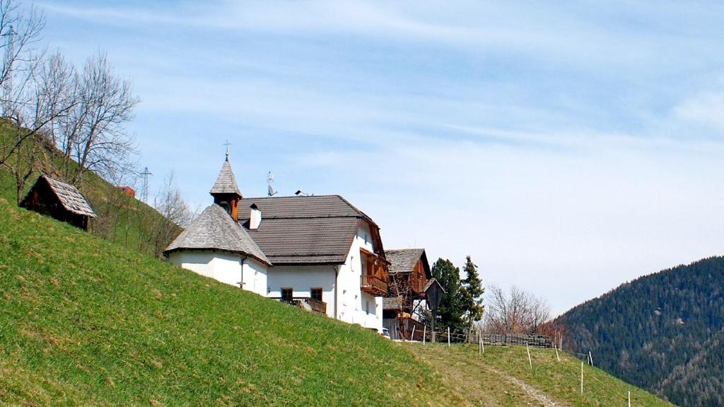 瓦尔道拉Berggasthof Trattes的山上的房子,上面有教堂