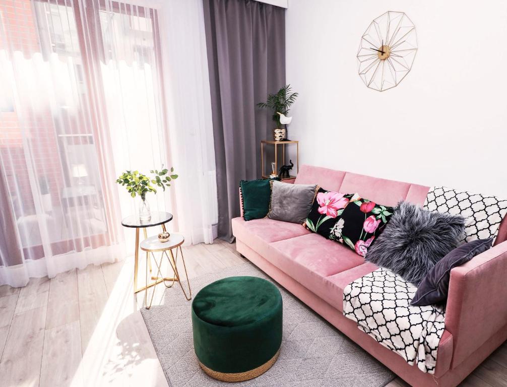 克拉科夫Apartament Arkadia na Kazimierzu的客厅配有粉红色的沙发和绿色的搁脚凳