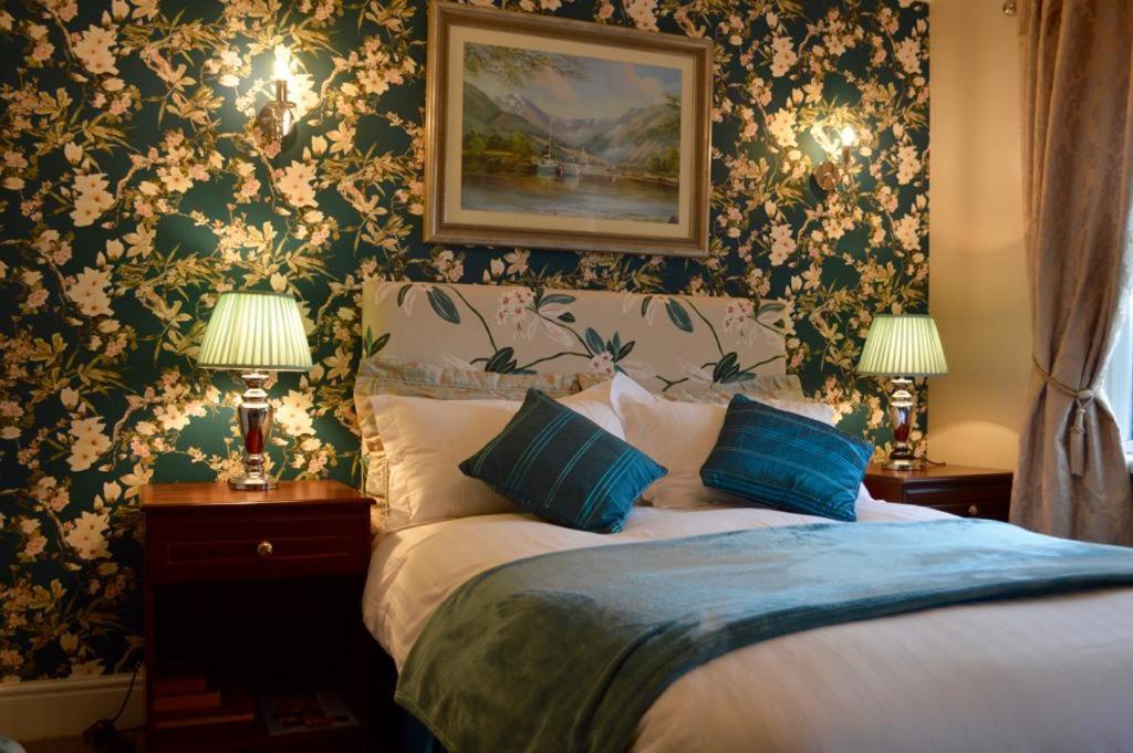 利斯纳龙科里里斯乡村酒店的一间卧室配有一张带蓝色枕头和花卉壁纸的床