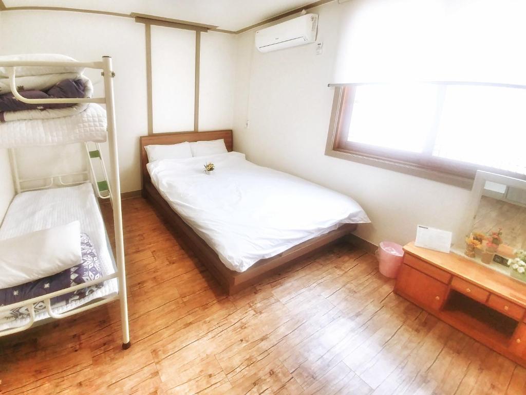 济州市Jeju Masil Guesthouse的一间卧室配有双层床,铺有木地板