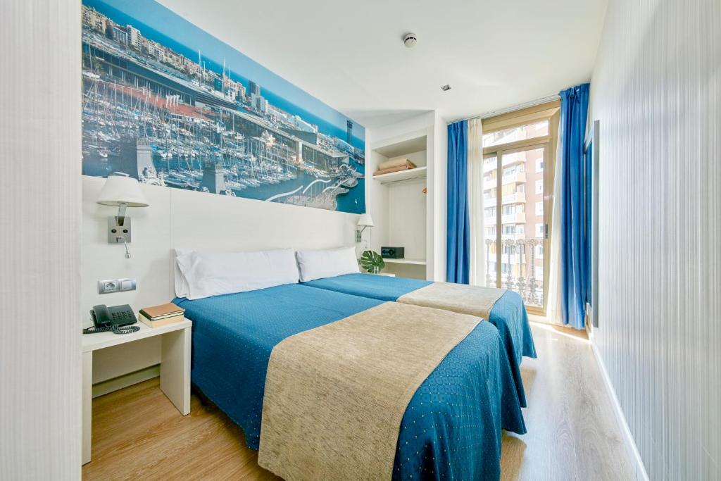 巴塞罗那途经酒店的卧室配有蓝色和白色的床和窗户。