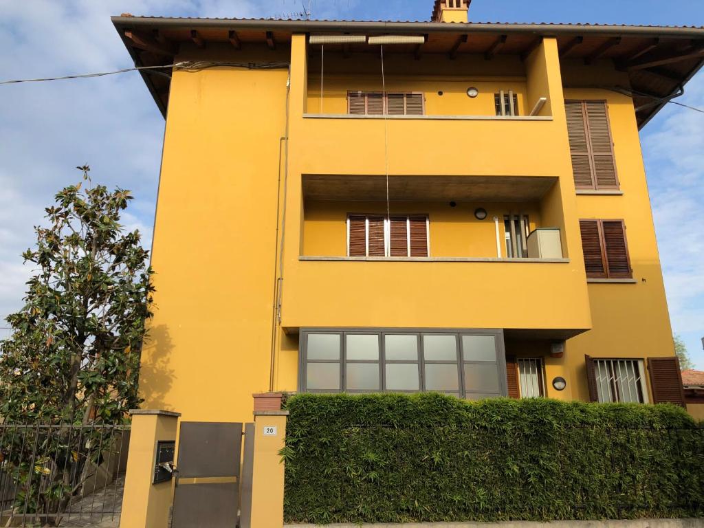 博洛尼亚Michelino's house的黄色的建筑,有窗户和树 ⁇ 