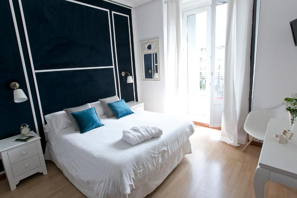 马德里格兰大道巴斯克斯德梅拉旅馆的卧室配有带蓝色枕头的大型白色床
