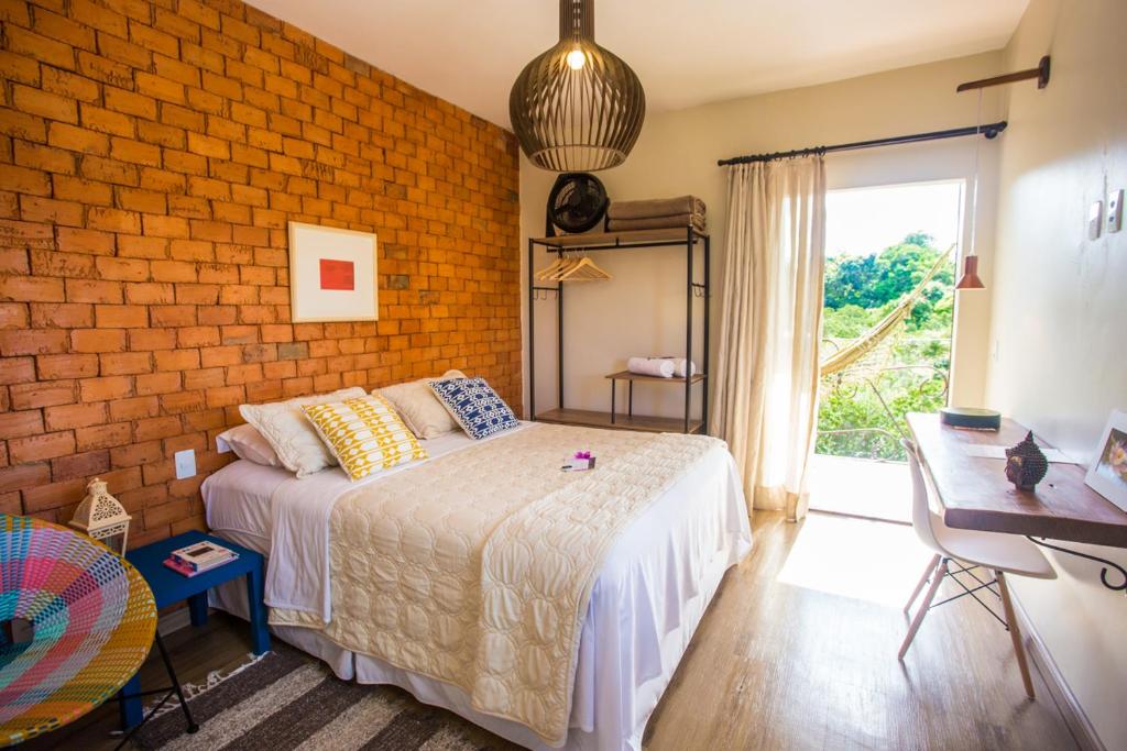戈亚斯州上帕莱索Vilarejo Guesthouse - Silêncio e Aconchego的一间卧室设有一张床和砖墙