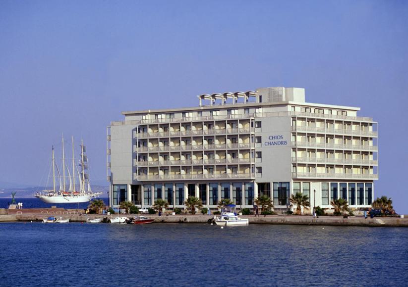 希俄斯希尔斯尚德里酒店的一座白色的大建筑,水中有船