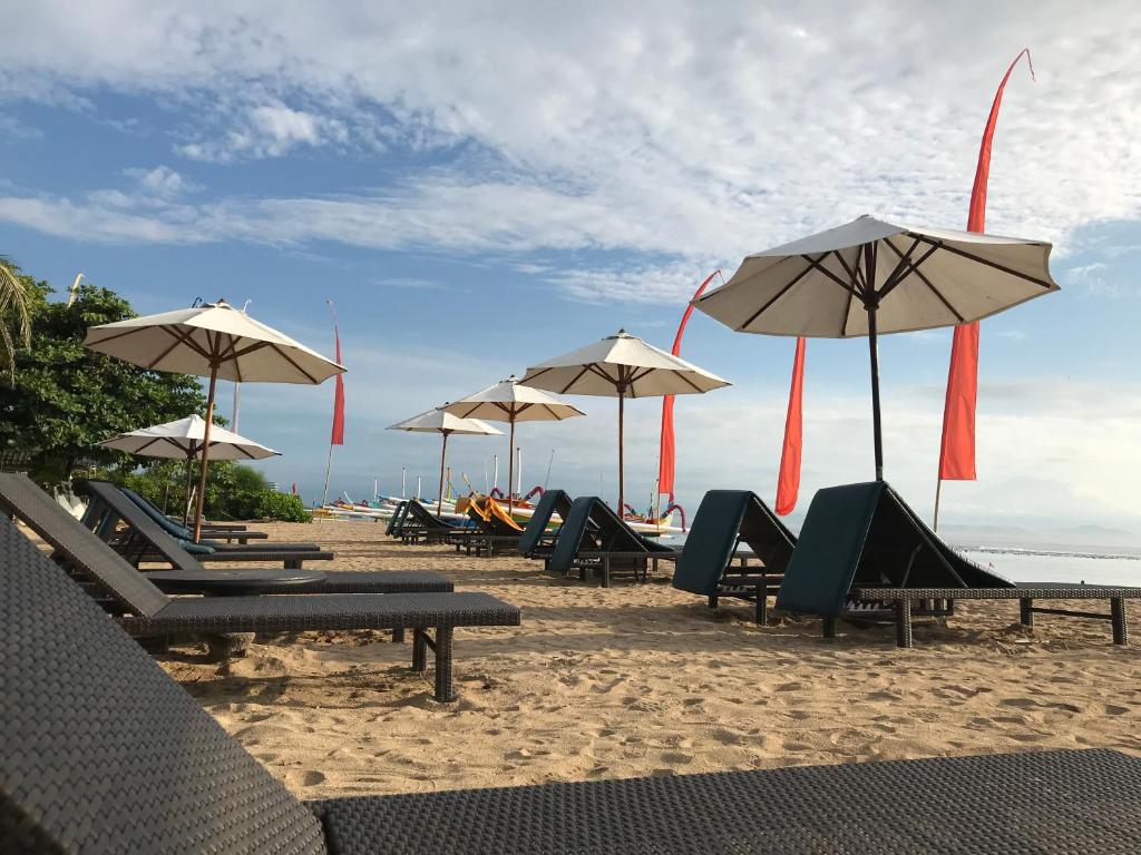 沙努尔Besakih Beach Hotel的海滩上的一组椅子和遮阳伞