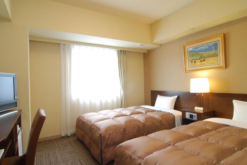 盐尻市盐尻市鹿特因酒店的酒店客房设有两张床和窗户。
