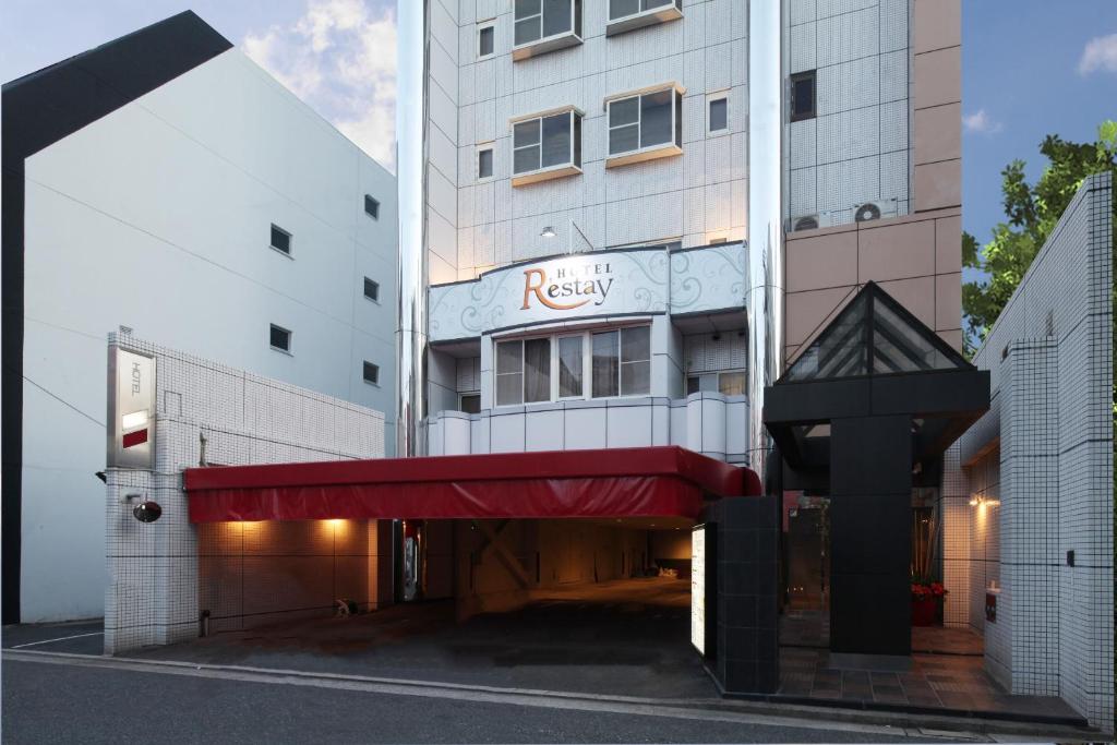 广岛Restay Hiroshima (Adult Only)的大楼前有红色遮阳篷的酒店