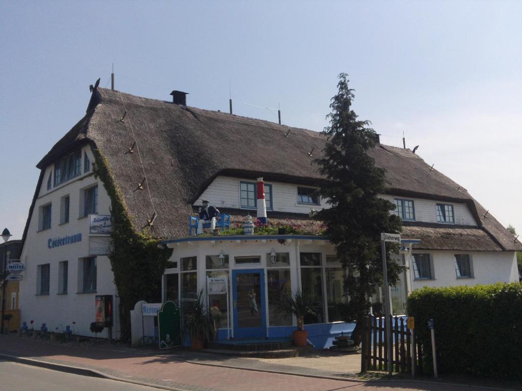 瓦尔内明德Landhotel Ostseetraum & Fewo的一座带茅草屋顶的古老白色建筑