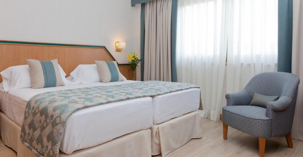 马德里布拉格酒店的一间卧室配有一张大床和一把椅子