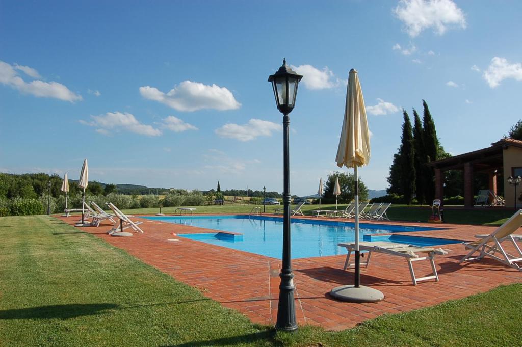 佩尔吉内-瓦尔达诺Agriturismo Il Palazzo的游泳池配有椅子、灯杆和遮阳伞