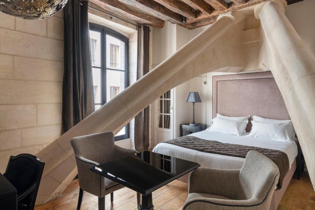 巴黎Hôtel Le Presbytère的卧室配有1张床、1张桌子和1把椅子