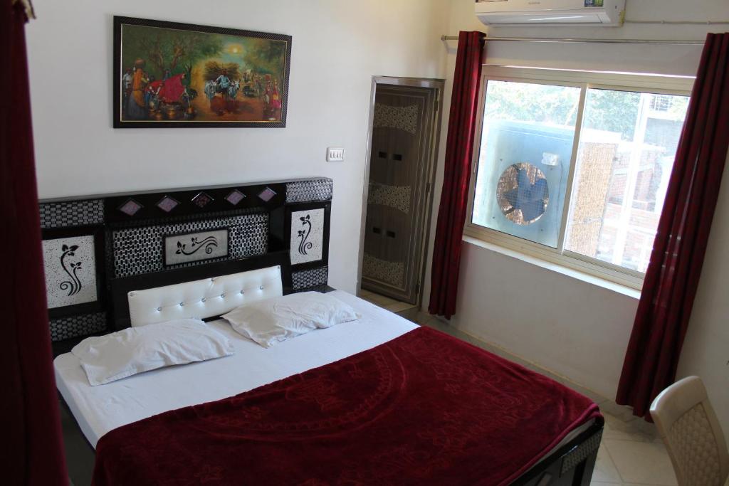 奥拉奇哈Best B&B in Orchha的一间卧室配有一张带红色毯子的床和窗户。
