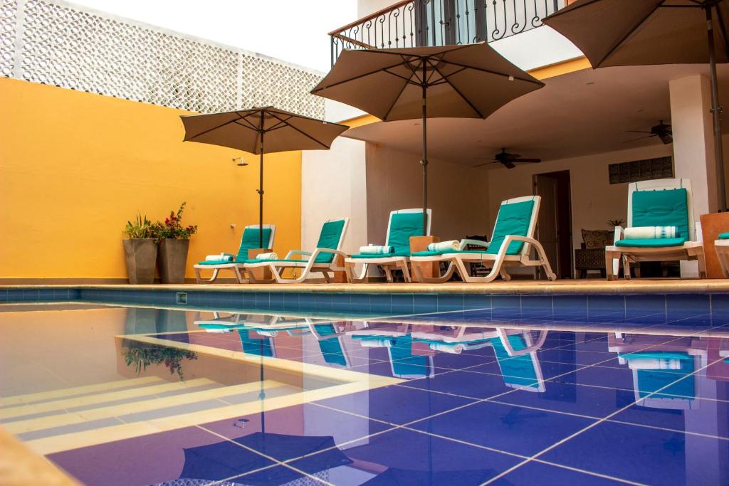 蒙波斯La Gloria Hotel by BespokeColombia的一个带蓝色椅子和遮阳伞的游泳池
