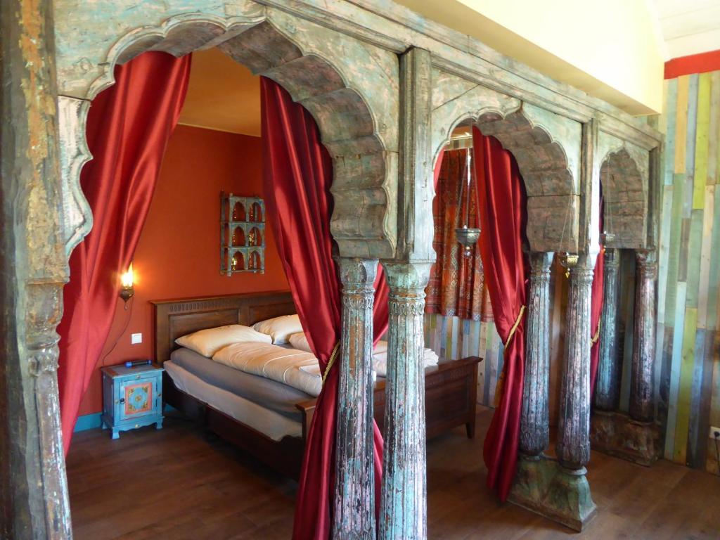 WelsumVakantiewoning 1001 Nacht的一间卧室配有一张带红色窗帘的天蓬床