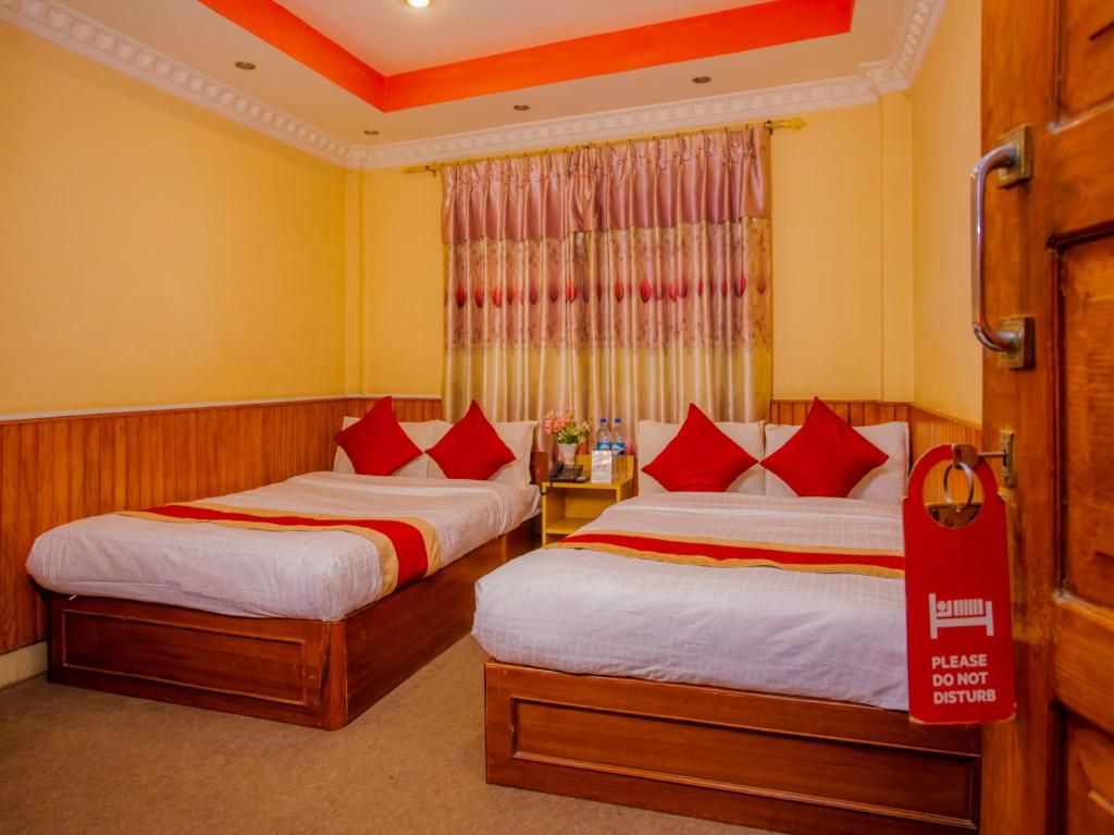 PashupatināthOYO 305 Hotel Gauri的酒店客房 - 带两张带红色枕头的床