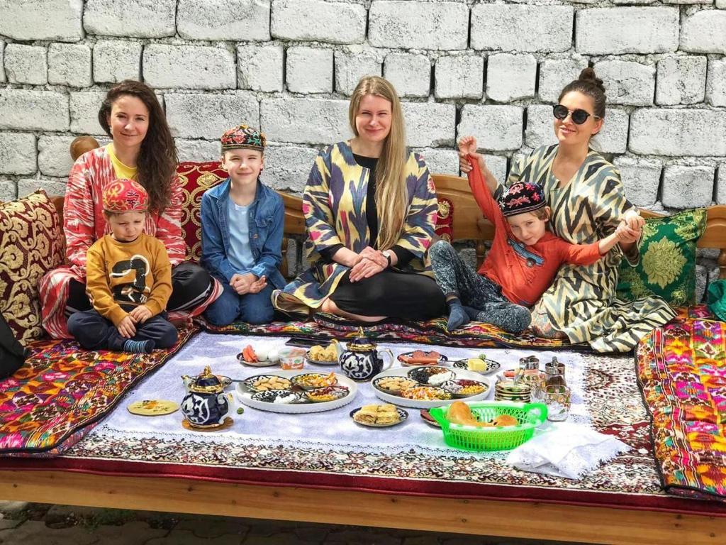 撒马尔罕World Guest House的一群人坐在长凳上吃着食物