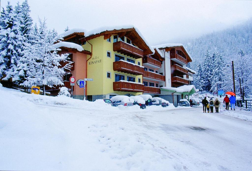 摩德纳迪-坎皮格里奥Hotel Bonapace ***S的一座有雪盖的建筑,前面的人在步行