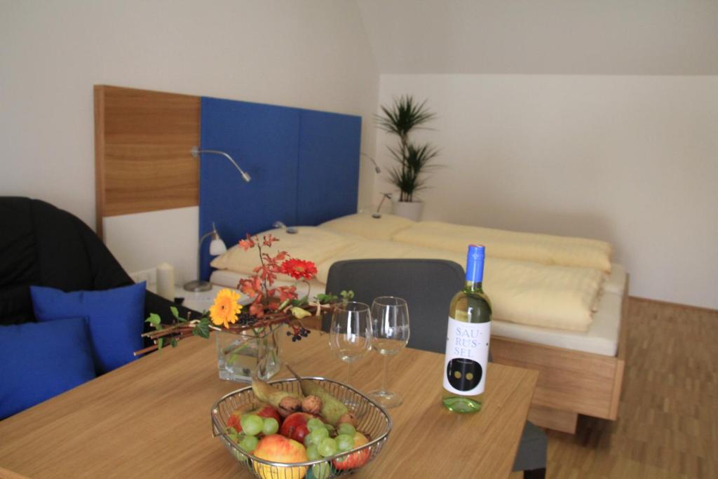 波伊斯多夫艾森胡特酒店的一间房间,配有一张桌子,提供一瓶葡萄酒和一碗水果