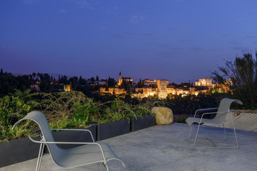 格拉纳达Luxury Cave 100m super terraza vistas Alhambra WIFI的两把椅子在晚上坐在庭院里