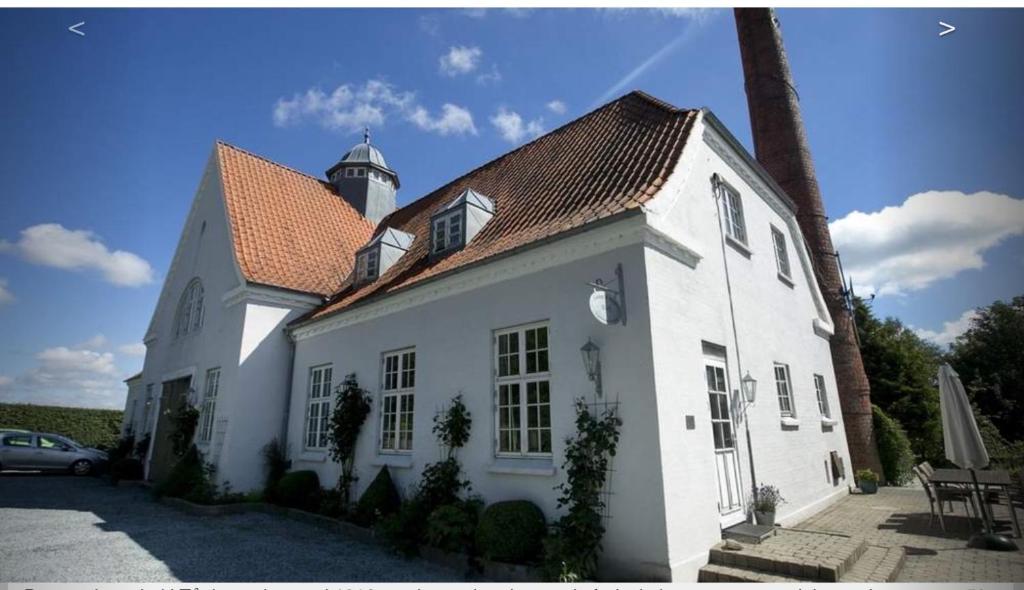斯坎讷堡Tåning Gl. Mejeri的白色的房子,上面有一个灯塔