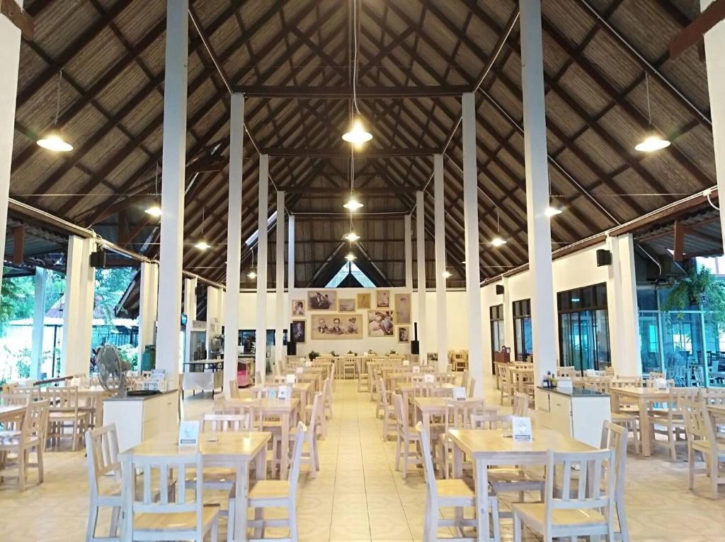 董里LayTrang Pakmeng Marina Spa and Resort的一个带桌子和白色椅子的用餐大厅