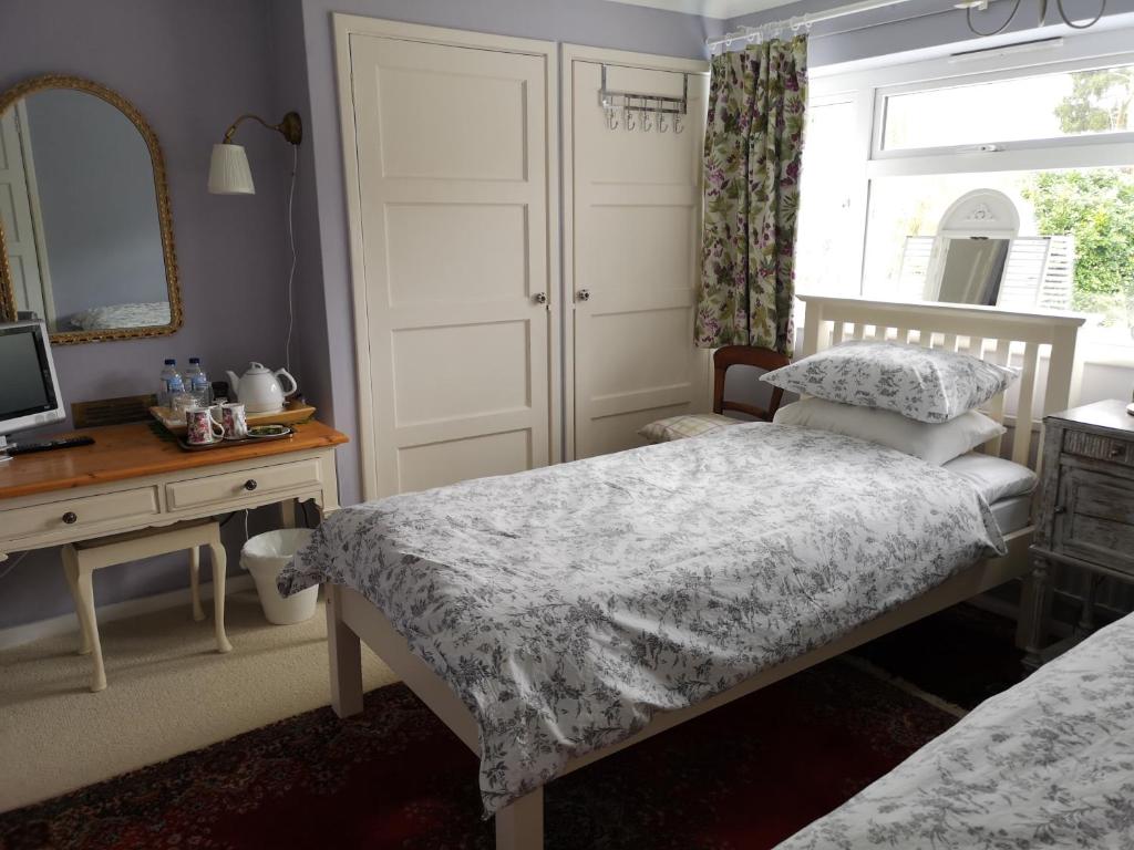 塞文欧克斯UPTHEDOWNS B&B的一间卧室配有两张床、一张桌子和一面镜子