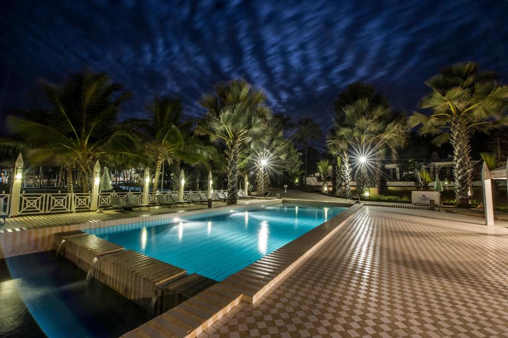 BijiloCoco Ocean Resort & Spa的游泳池,在晚上有棕榈树和灯光