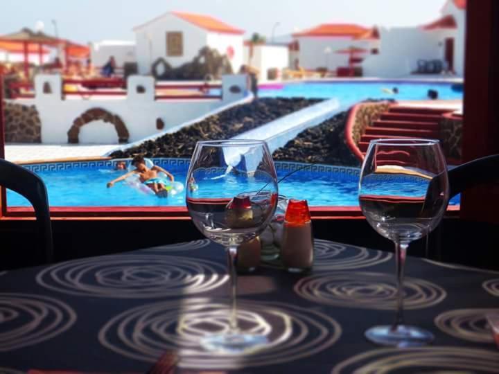 卡勒达德福斯特卡斯蒂约海滩洋房酒店的两个酒杯坐在游泳池旁的桌子上
