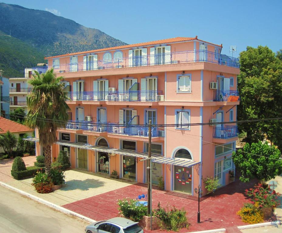 波罗斯安妮莫斯公寓式酒店的粉红色的建筑,设有蓝色的阳台,位于街道上
