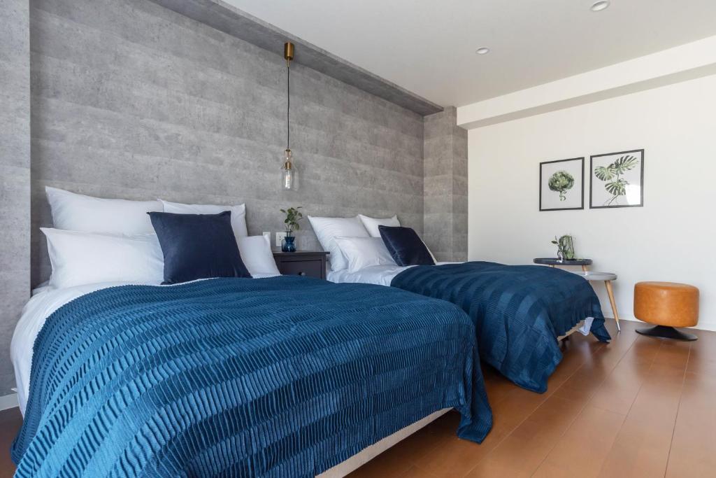 大阪Villa Penthouse Tenma的卧室内的两张床,配有蓝色和白色的床单