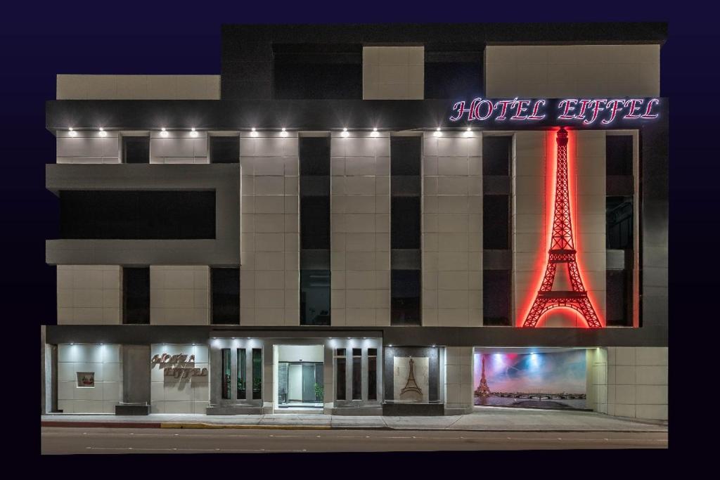 恩塞纳达港HOTEL EIFFEL的一座晚上有艾菲尔铁塔的建筑