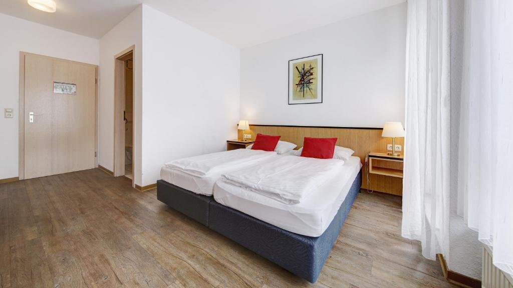 莱因费尔登-埃希特尔丁根斯特滕机场酒店的一间卧室配有带白色床单和红色枕头的床。