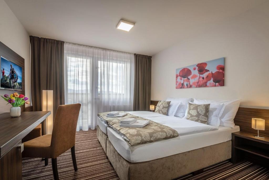 波普拉德Hotel SATEL的酒店客房设有一张大床、一张书桌和一张书桌。