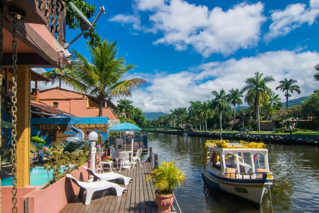 帕拉蒂Pousada Casa do Rio Hostel - 8 min do Centro Hístorico - Passeio de Barco com saída da Pousada -Pago a parte- Perto das Praias e Beira Rio的一条河,船停靠在度假村旁边