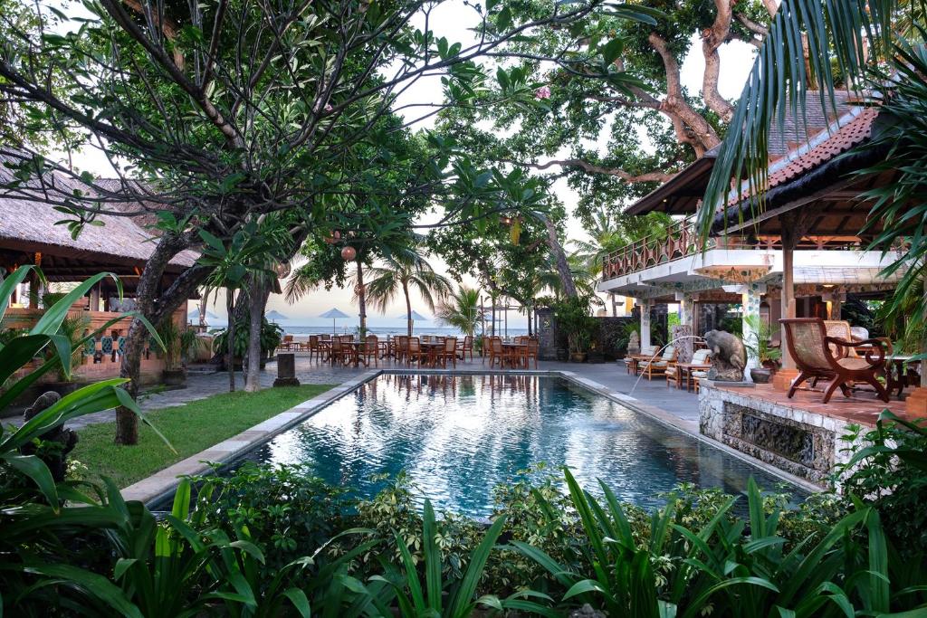 沙努尔丹戎乌萨里酒店的一个带桌椅的度假村游泳池