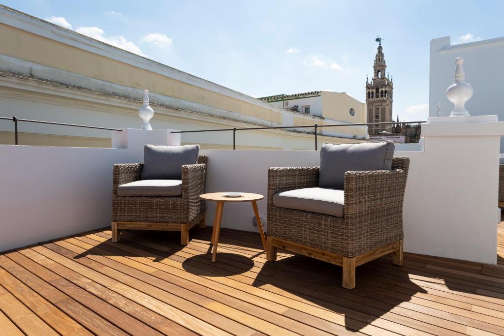 塞维利亚Basic Hotel Sevilla Catedral的阳台配有2把椅子和1张桌子