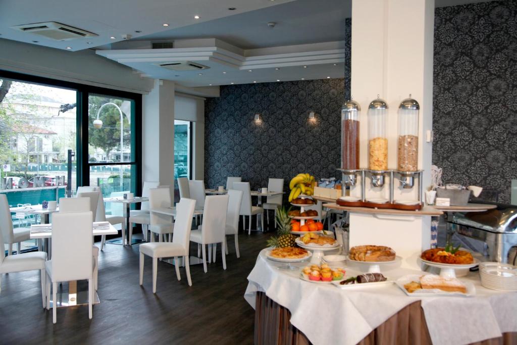 里乔内Hotel Montecarlo - Vista Mare con Piscina & Area Fitness的一间餐厅配有桌椅,提供食物