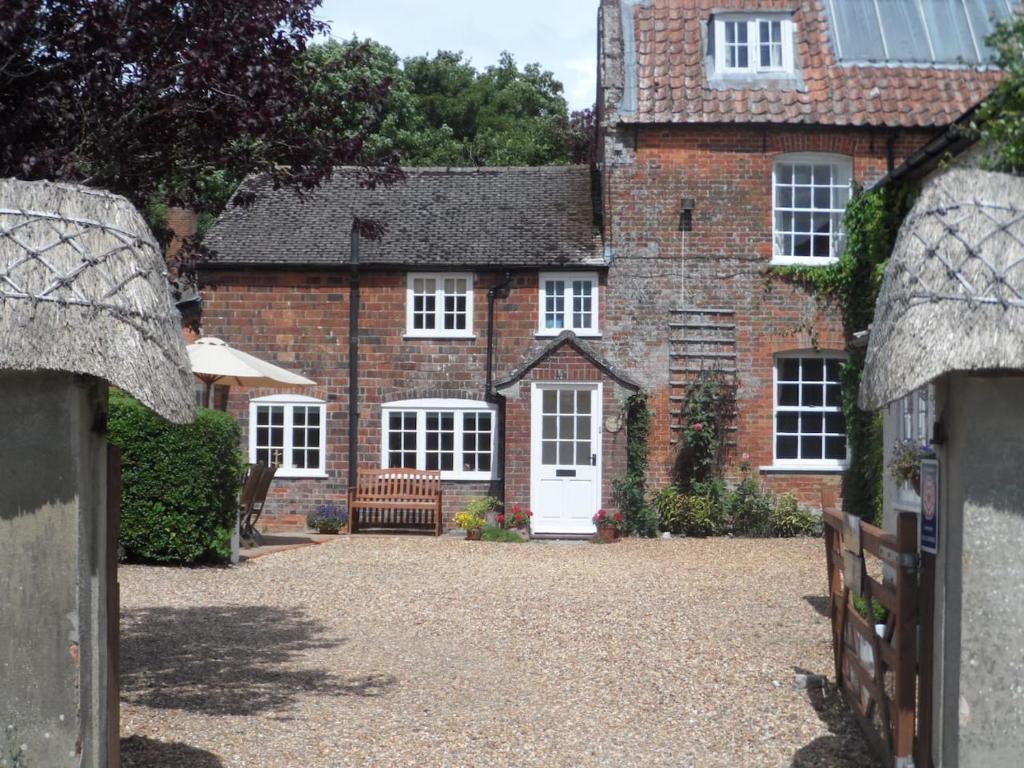 PewseyStunning 3 bedroom 3 bath self catering cottage near Stonehenge Avebury and Bath Great village pub的白色门的大砖屋