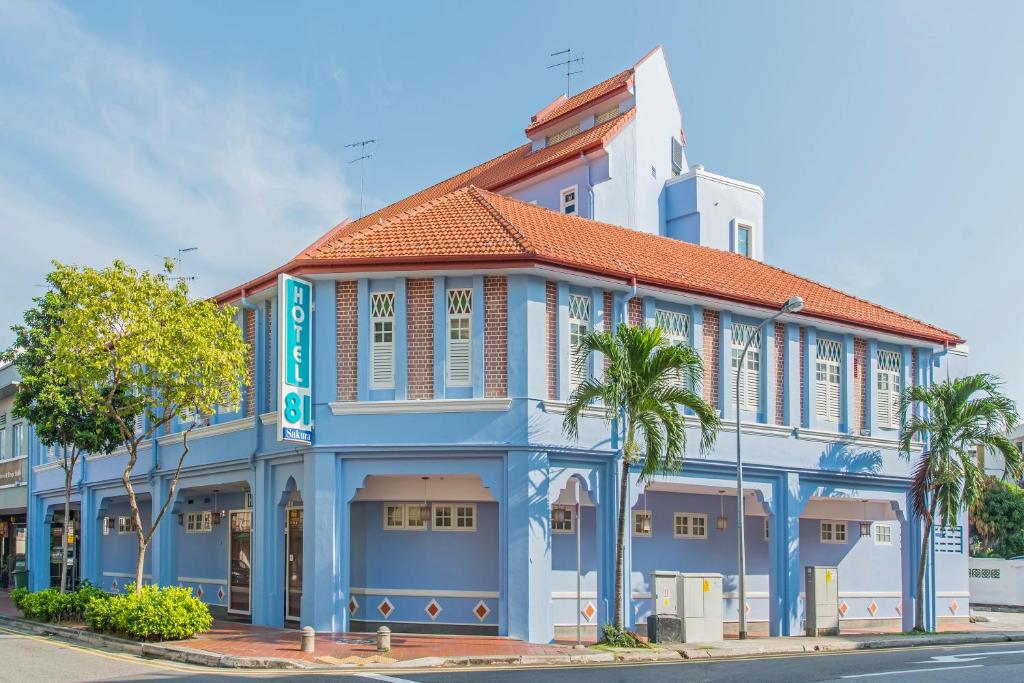 新加坡Hotel 81 Sakura的一座蓝白色的建筑,前面有棕榈树