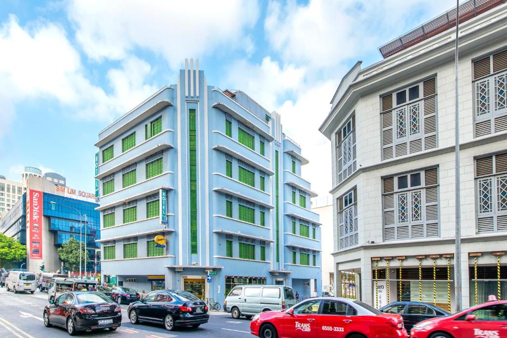 新加坡新加坡81酒店 - 梧槽的一座高大的白色建筑,前面有汽车停放