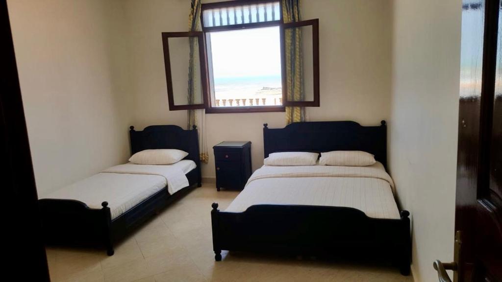 西迪伊夫尼HOTEL BEACH CLUB LEGZIRA的带窗户的客房内的两张床