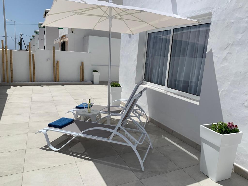 圣巴尔托洛梅Princesa Ico, cerca del mar的阳台上的白色椅子和遮阳伞